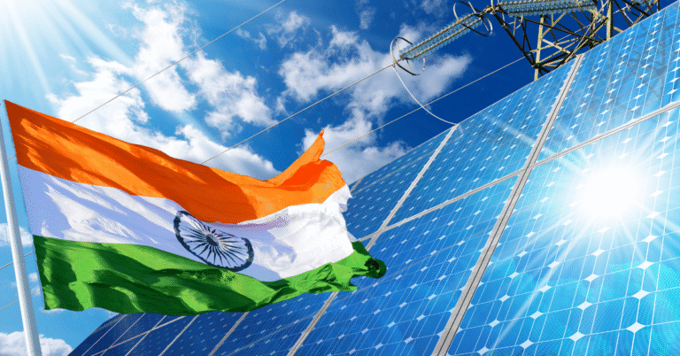 India’s position on Climate Change: The emerging voice of Global South The Indian flag waves in front of large solar panels and an electricity pylon under a sunny sky, illustrating India's Position on Climate Change.