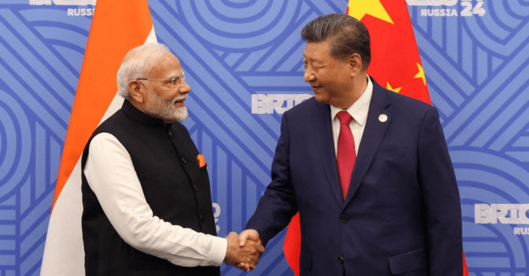 Indian Prime Minister Narendra Modi and Chinese President Xi Jinping shaking hands in front of their respective national flags during a bilateral meeting, highlighting the strategic relationship between India and China.